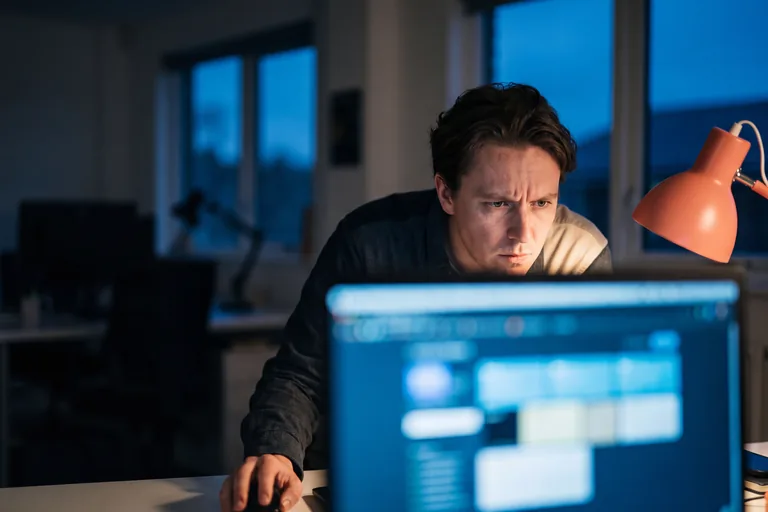 A media buyer studying campaign performance on screen in a darkened office