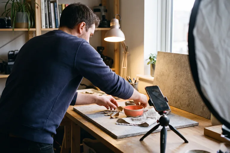 A creator setting up a phone on a tripod to shoot content in a home studio
